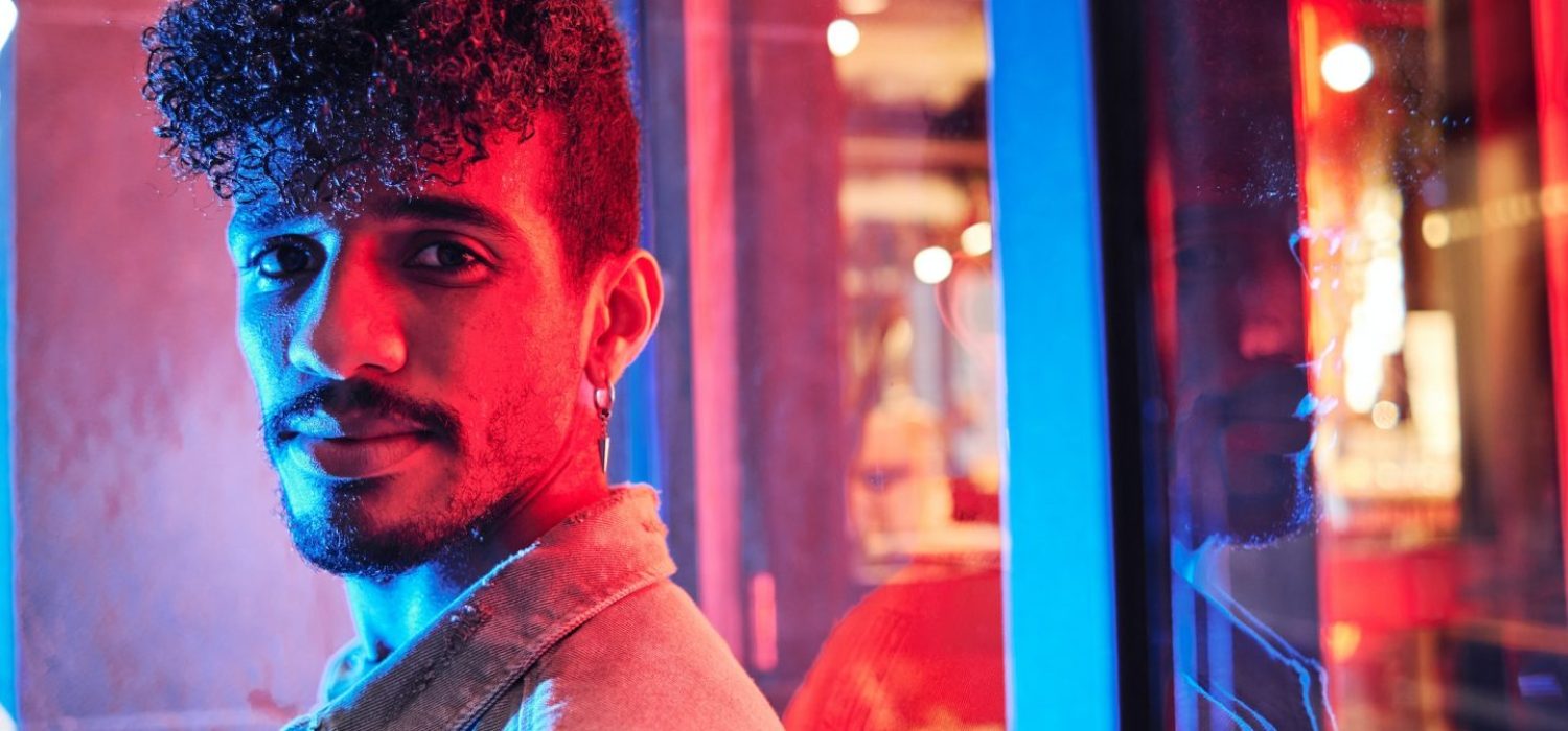 young-hispanic-man-close-to-a-neon-light-with-blue-and-red-lights-e1698314047406.jpg